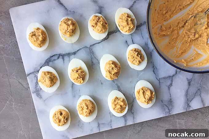 Chipotle Deviled Eggs with Smoky-Spicy Kick 8 Horizontal image of a marble board with filled egg halves with a red filling