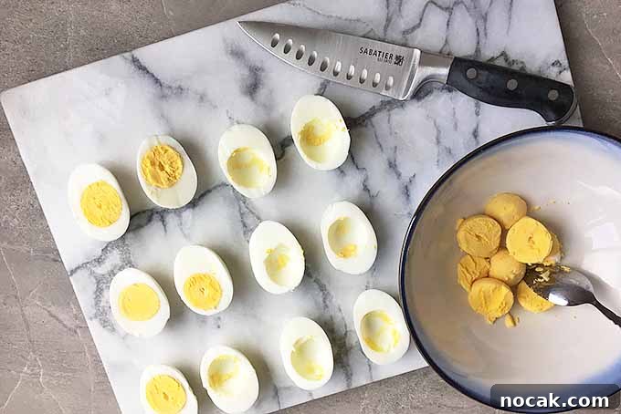 Chipotle Deviled Eggs with Smoky-Spicy Kick 6 Horizontal image of a knife with egg halves and a bowl of yolks