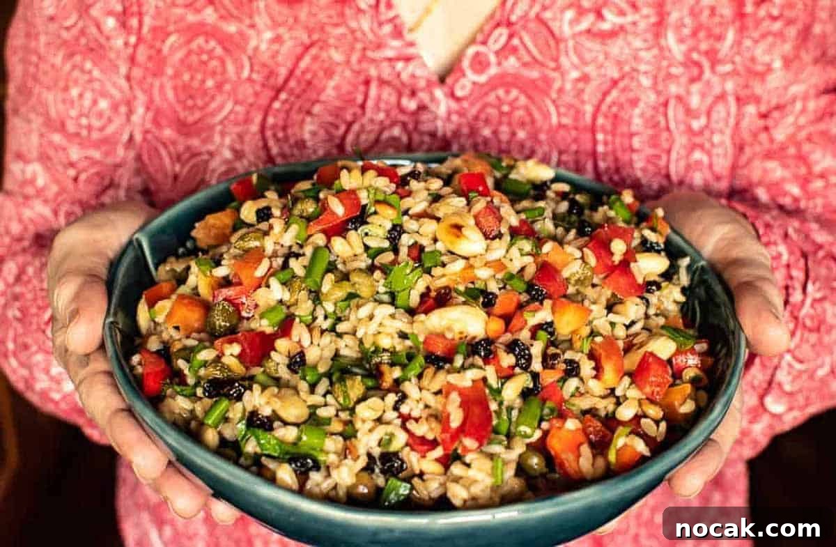 Hearty Brown Rice Salad with Fresh Veggies and Lemon Vinaigrette 3 Woman in red shirt holding bowl of salad.