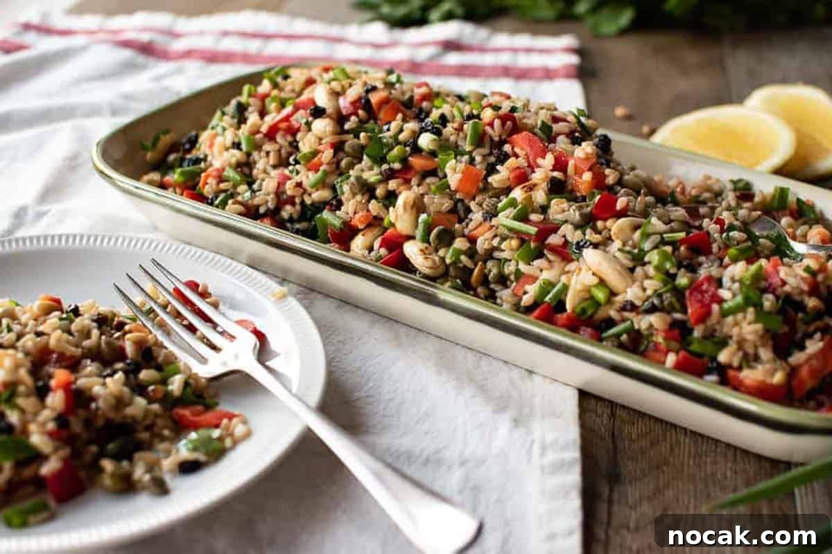 Hearty Brown Rice Salad with Fresh Veggies and Lemon Vinaigrette 5 A white dish with a portion of the salad served and the serving bowl.