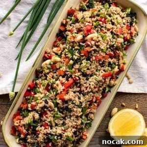 Hearty Brown Rice Salad with Fresh Veggies and Lemon Vinaigrette 6 salad in oblong plate with spring onions and lemon.