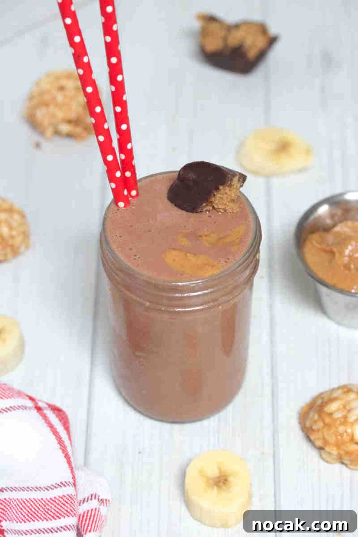 Peanut Butter Cup Protein Shake — 22g Protein Per Serving 2 Chocolate peanut butter cup smoothie in mason jar topped with peanut butter cup and red straws in it.