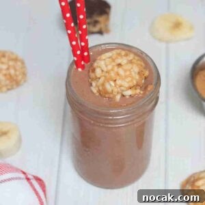 Peanut Butter Cup Protein Shake — 22g Protein Per Serving 13 Chocolate peanut butter cup smoothie in mason jar topped with peanut butter bomb in it and red straws in it.