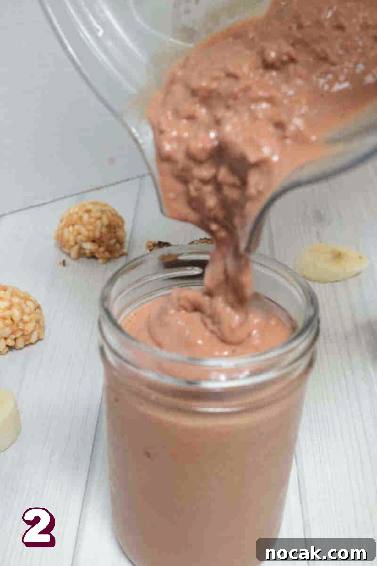 Peanut Butter Cup Protein Shake — 22g Protein Per Serving 5 Chocolate peanut butter protein shake being poured into a mason jar.