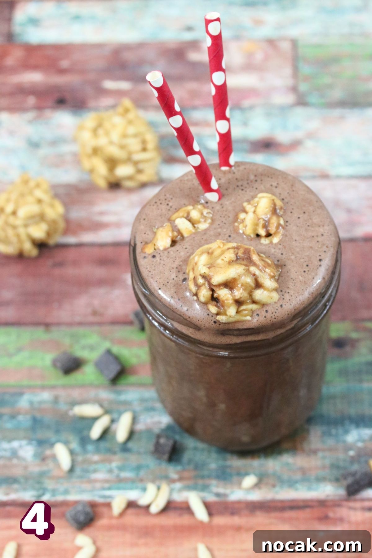 Peanut Butter Cup Protein Shake — 22g Protein Per Serving 7 Chocolate peanut butter shake in a mason jar with peanut butter balls on top and red straws.