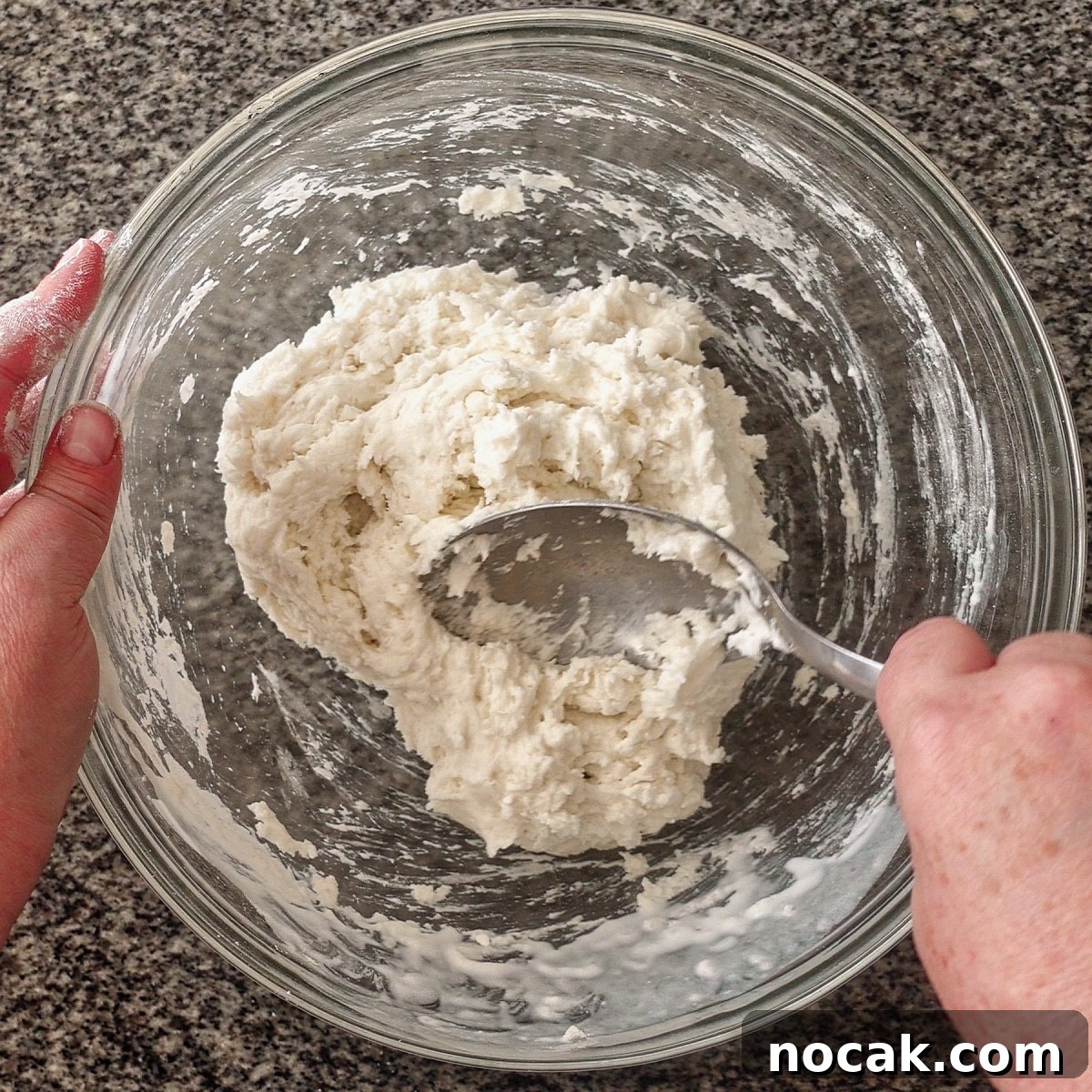 bringing dough together with spoon in large glass bowl.