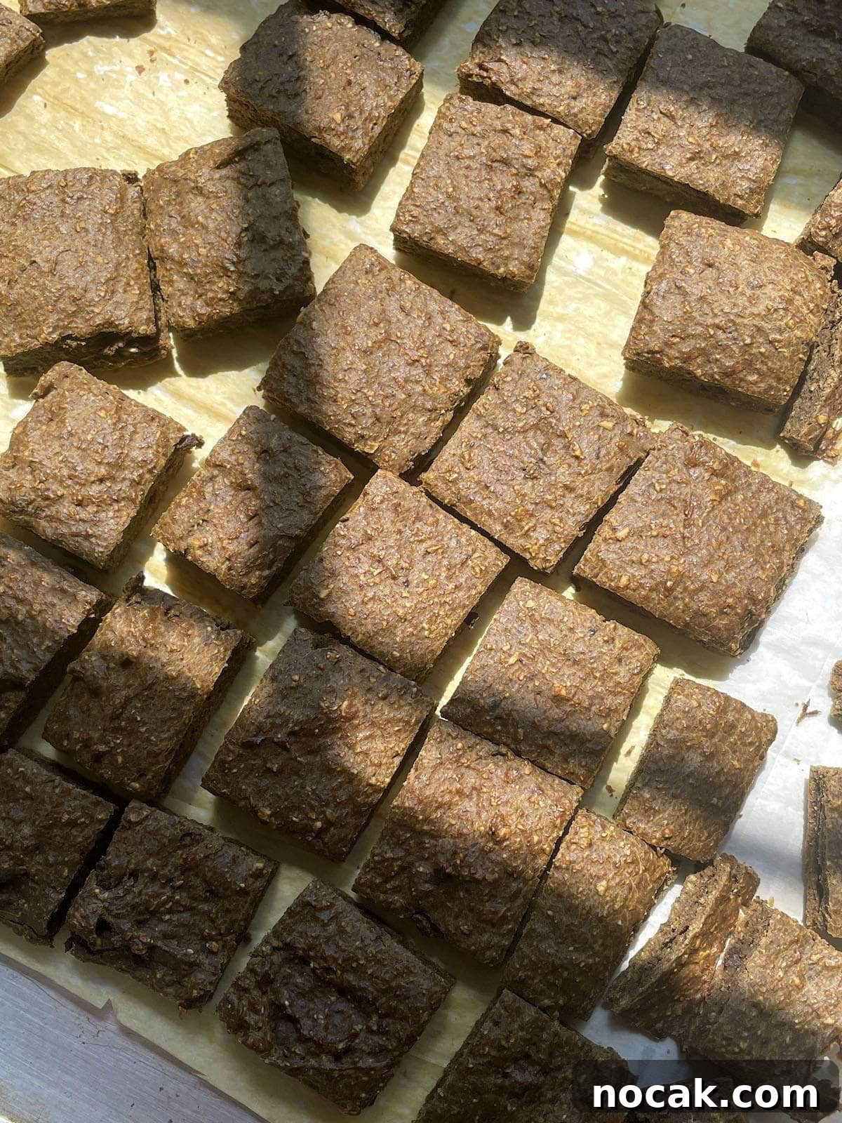 Homemade Liver Brownies: Irresistible Dog Treat Recipe 13 A pan with parchment paper on it covered in cut up liver brownie treats for dogs.