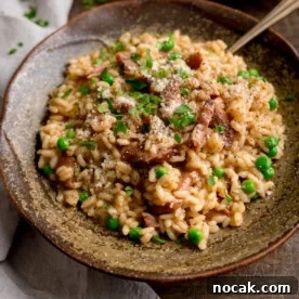 Square image of Ham and Pea Risotto served in a rustic brown bowl. There is a fork sticking out.