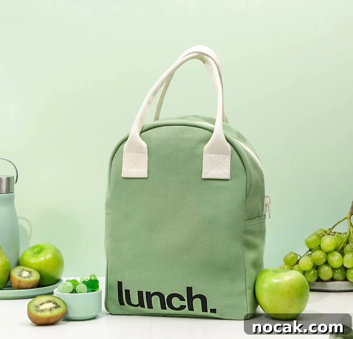 A mint-colored, eco-friendly organic lunch bag for adults by Fluf, accompanied by fresh fruit and snacks