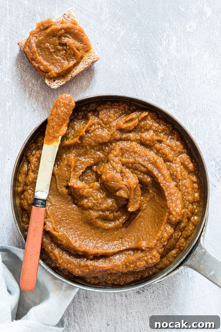 Slow-Cooker Pumpkin Butter Recipe for Fall Spreads and Gifts 3 top down view of the completed pumpkin butter with a knife spreading a portion onto a cracker