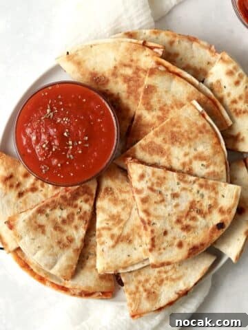 Plate of pizza quesadillas with marinara and pepperoni.