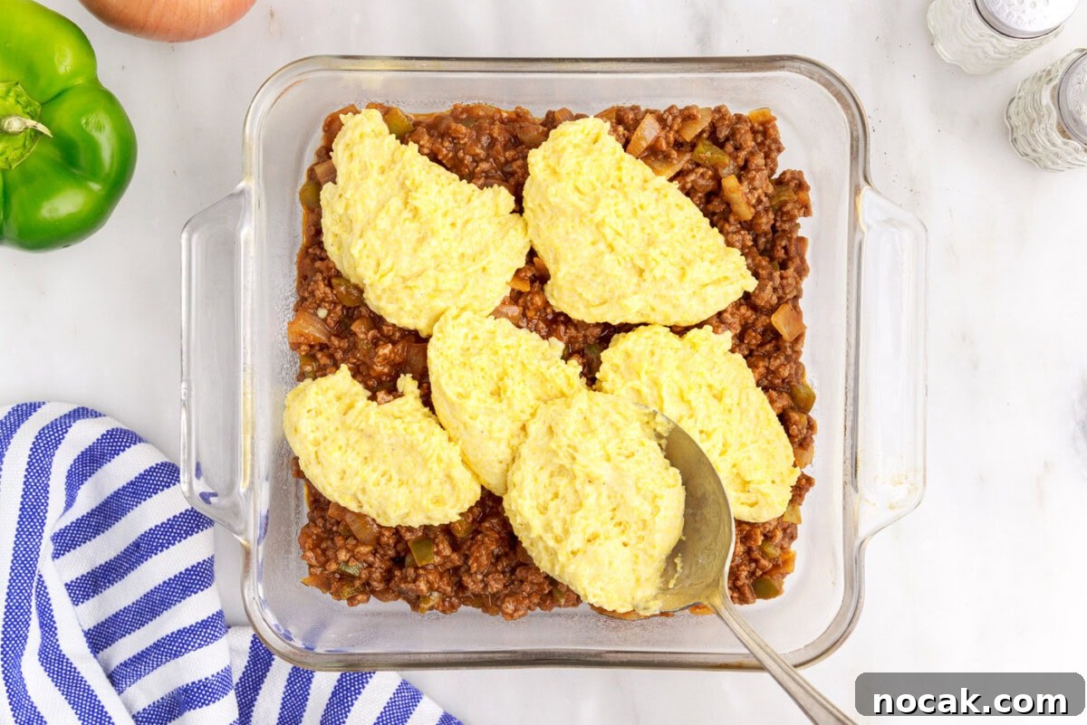 Sloppy Joe Casserole with Cheesy Cornbread Topping 9 cornbread mixture over sloppy joe meat in a baking dish