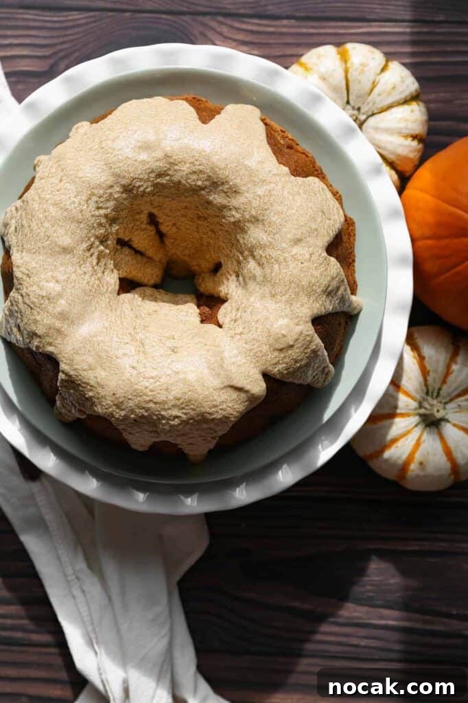 Gluten-Free Pumpkin Spice Bundt Cake Recipe for Fall Gatherings 2 a gluten free pumpkin spice bundt cake on a cake stand surrounded by mini pumpkins