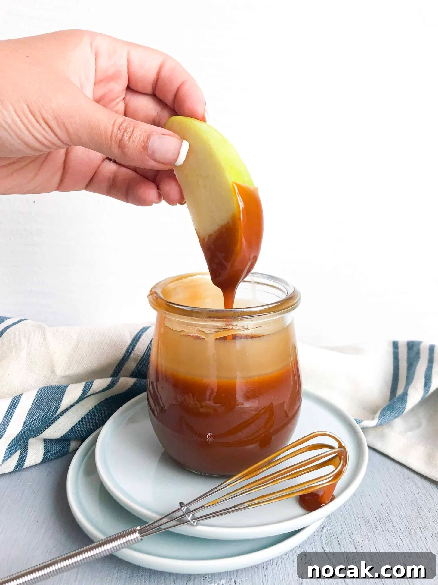 Homemade Caramel Sauce Recipe for Rich, Silky Drizzle 7 A green apple dipping into a jar of caramel