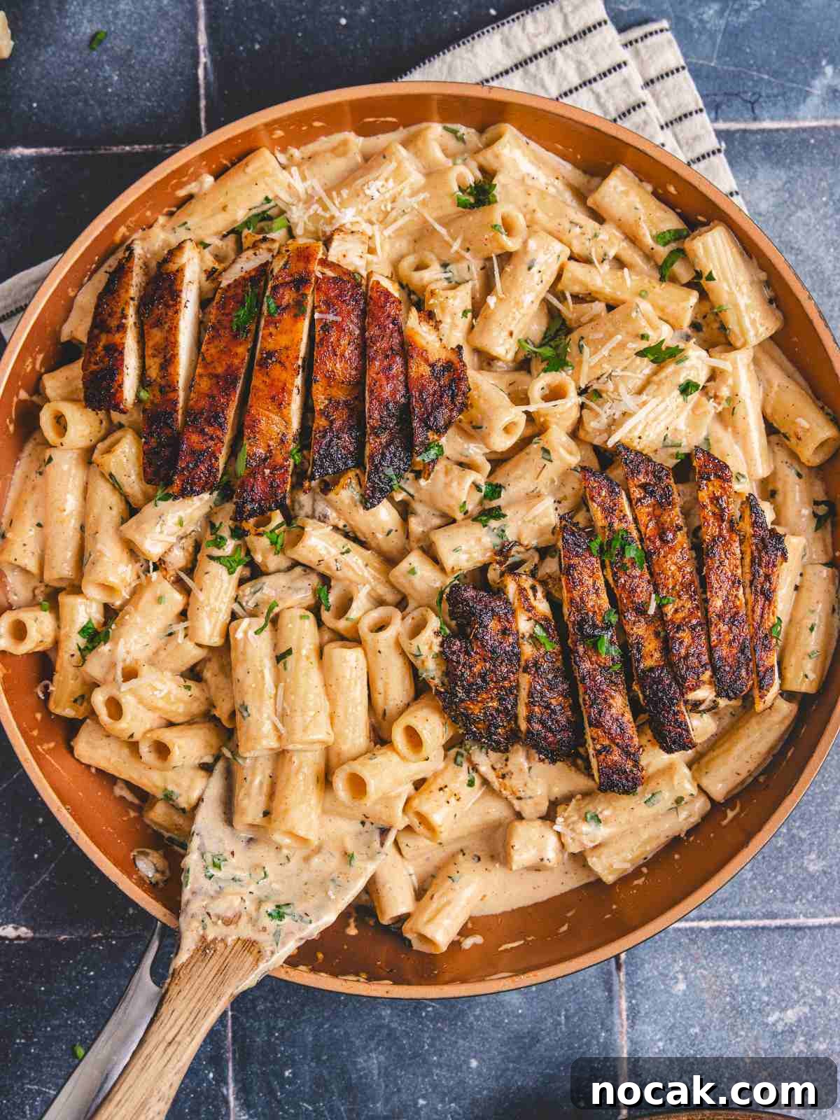 Blackened Chicken Alfredo Pasta Recipe: Creamy Cajun-Style Dinner 2 blackening Chicken alfredo in a pan with wooden spoon.