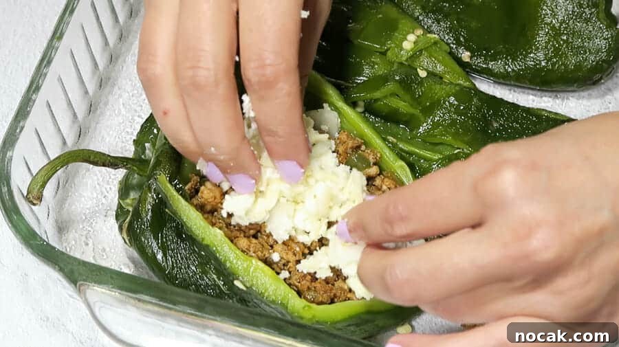 Baked Poblano Chiles Rellenos with Turkey Taco Filling 16 chiles rellenos being stuffed with cheese mixture