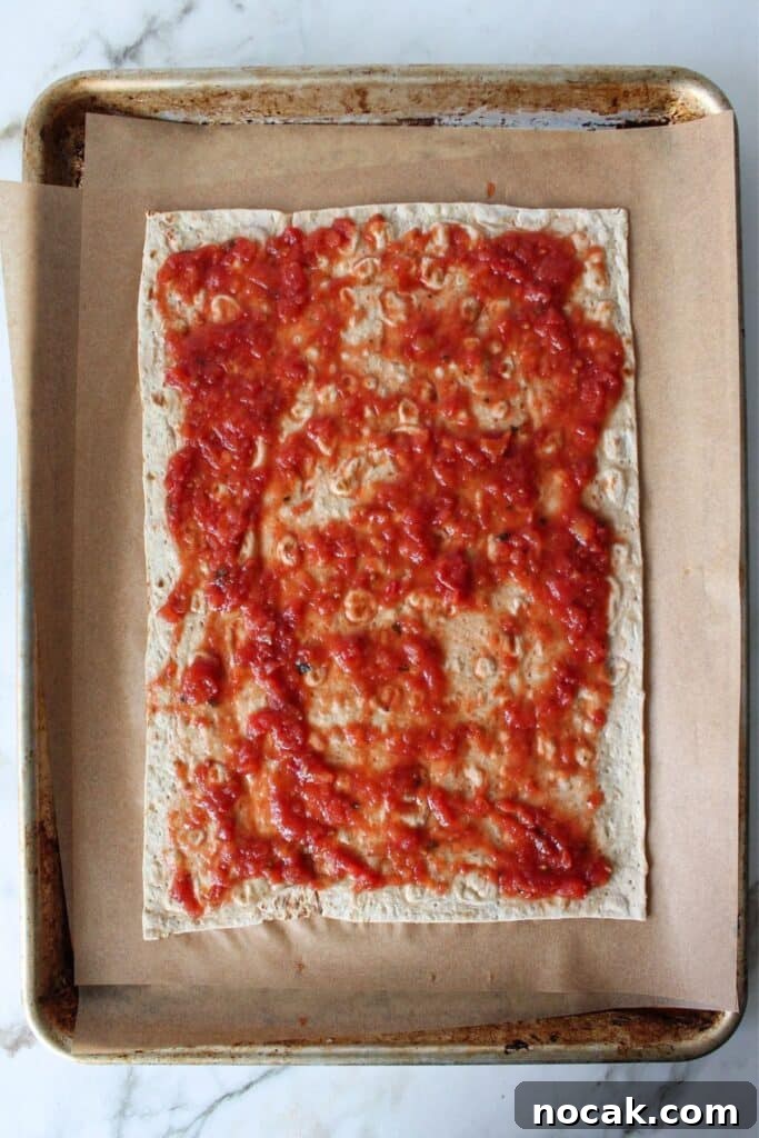 High-Protein Lavash Pizza Ready in 10 Minutes 4 A process shot of lavash bread pizza with lavash bread topped with sauce.