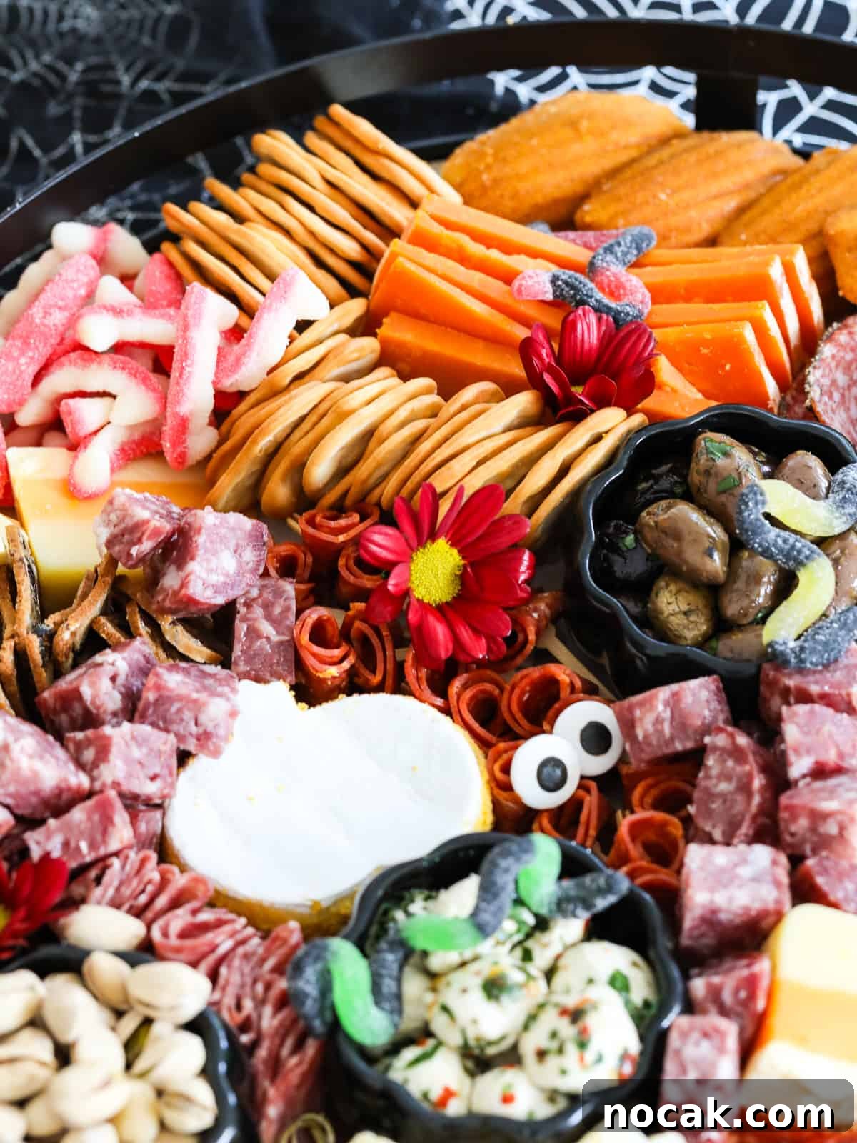 Spooky Halloween Charcuterie Board Ideas for Your Party 11 A large Halloween Charcuterie cheeseboard loaded with stacks of crackers, cut and sliced meats, nuts, and Halloween candy for a Halloween party.