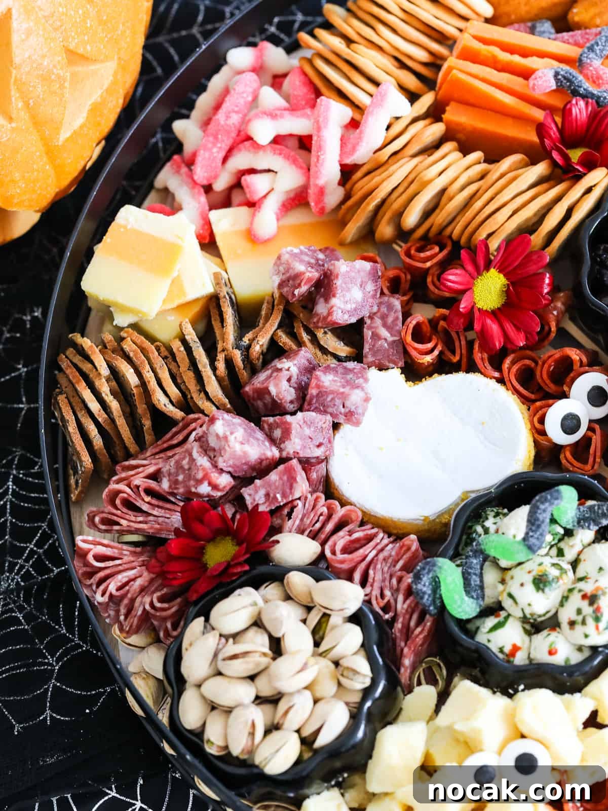 Spooky Halloween Charcuterie Board Ideas for Your Party 21 Looking down on a Halloween charcuterie board with pumpkin shaped brie cheese, stacks of crackers, sliced cheeses, nuts, and spooky Halloween candy.
