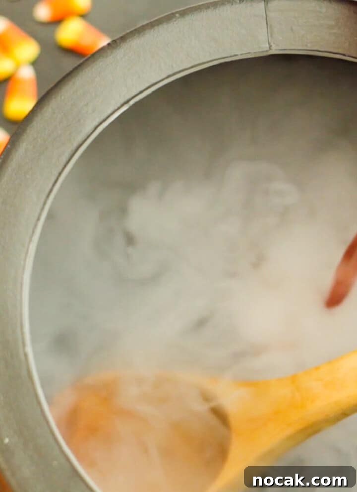 A black cauldron with pouring red punch and dry ice smoke for Halloween punch.
