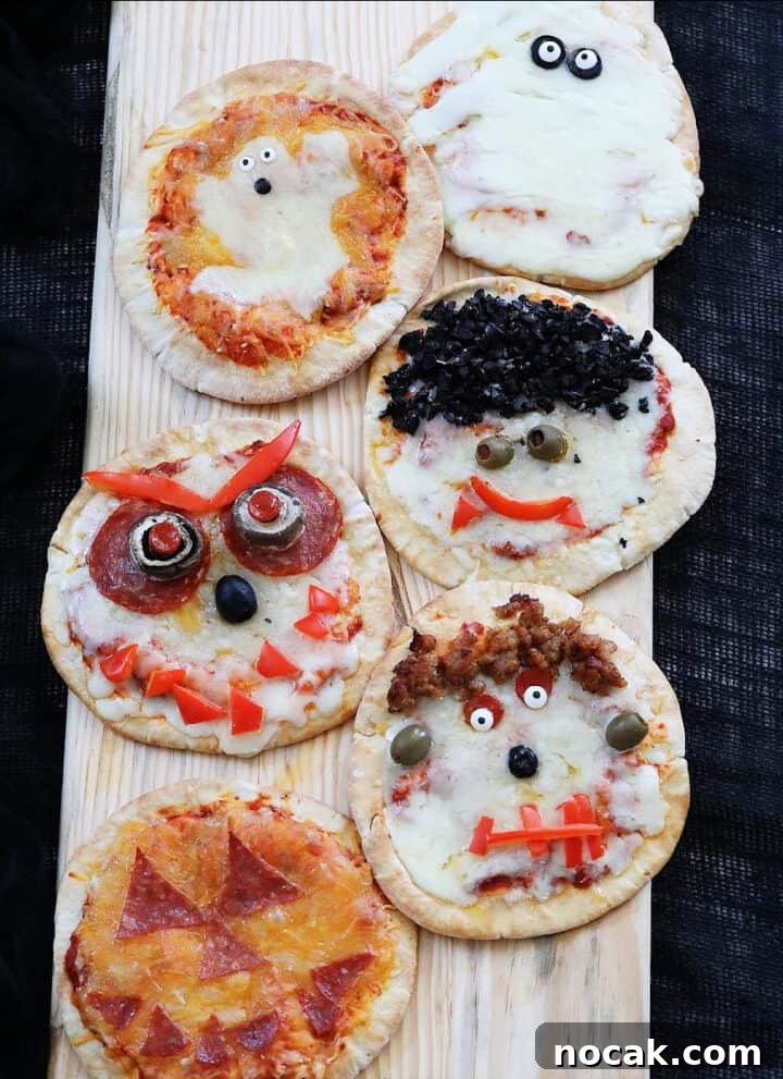 Six baked Halloween pizzas decorated like ghosts and pumpkins.
