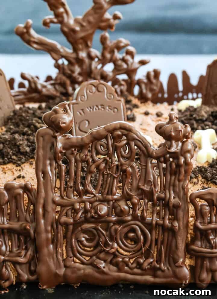 A chocolate Halloween cake with gate and tombstones.