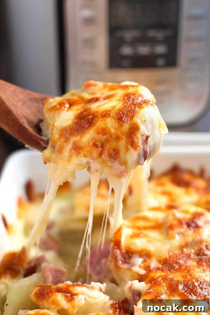 Thanksgiving Recipes for Instant Pot: Fast Holiday Favorites 9 Wooden spoon serving Scalloped Potatoes from a white baking dish in front of a pressure cooker