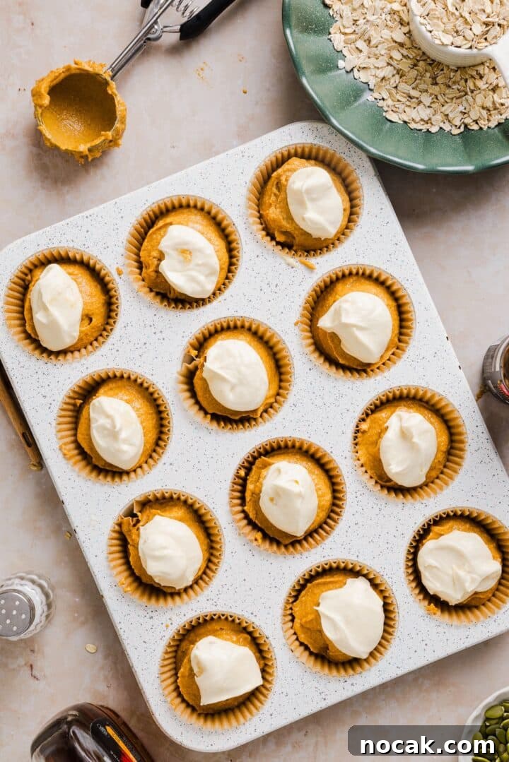 Pumpkin Cream Cheese Muffins with Swirled Filling and Spice 6 Pumpkin oatmeal muffins in a muffin tin, with cream cheese on top.