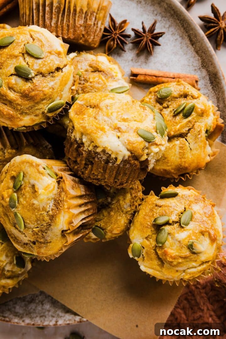 Pumpkin Cream Cheese Muffins with Swirled Filling and Spice 8 Pumpkin cream cheese muffins on a plate with pumpkin spice decor.