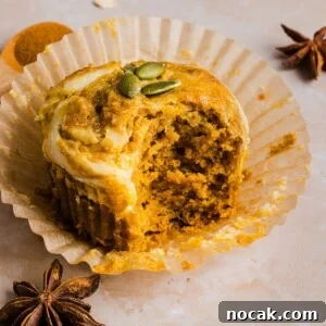 Pumpkin Cream Cheese Muffins with Swirled Filling and Spice 9 Pumpkin Oatmeal Muffin with cream cheese swirl in a paper muffin liner, on a marble counter.