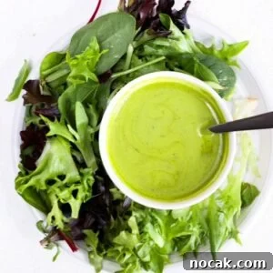 Basil Balsamic Vinaigrette Recipe — Fresh Homemade Dressing 5 A lettuce salad on a round white plate with a small white bowl of basil balsamic dressing.