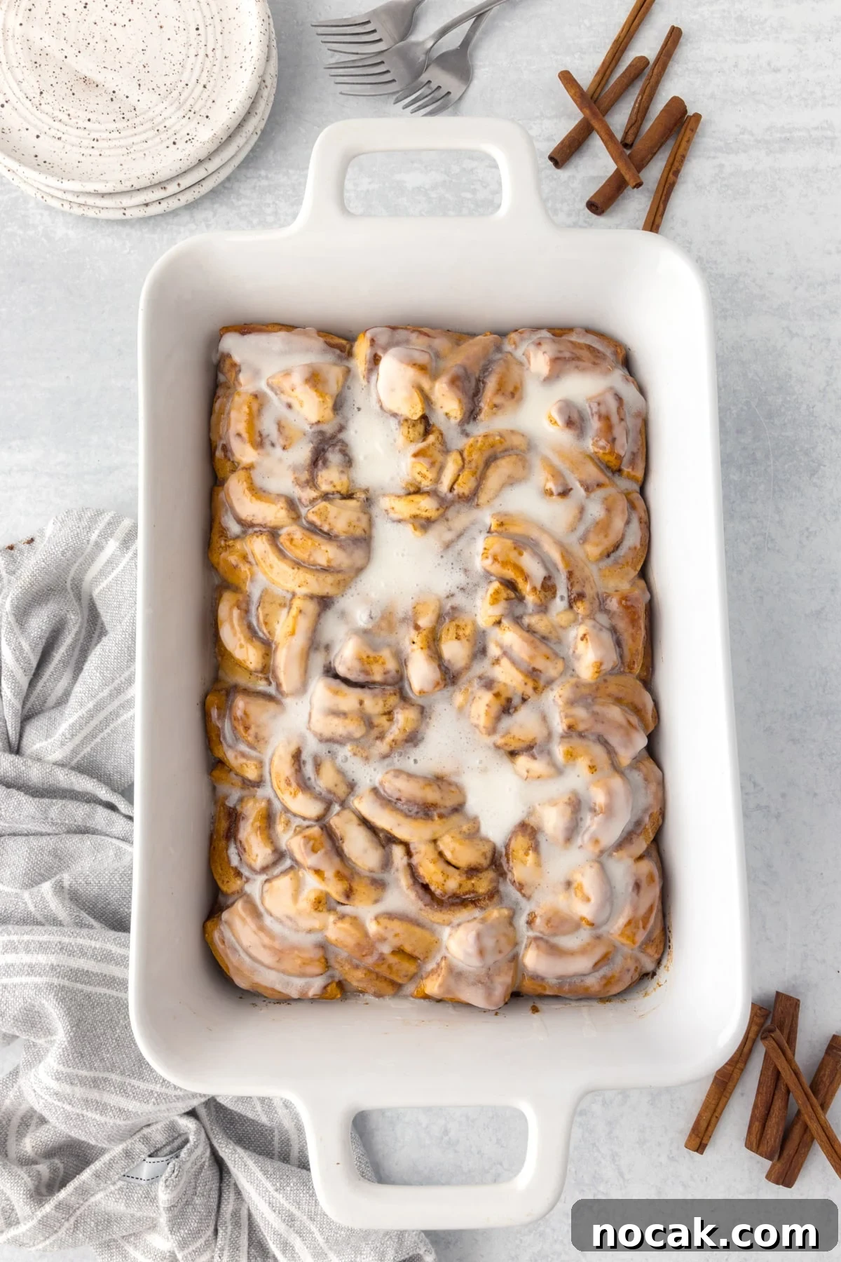 Cinnamon Roll Casserole Breakfast Bake Recipe 11 A baking dish filled with cinnamon roll bake, topped with icing.