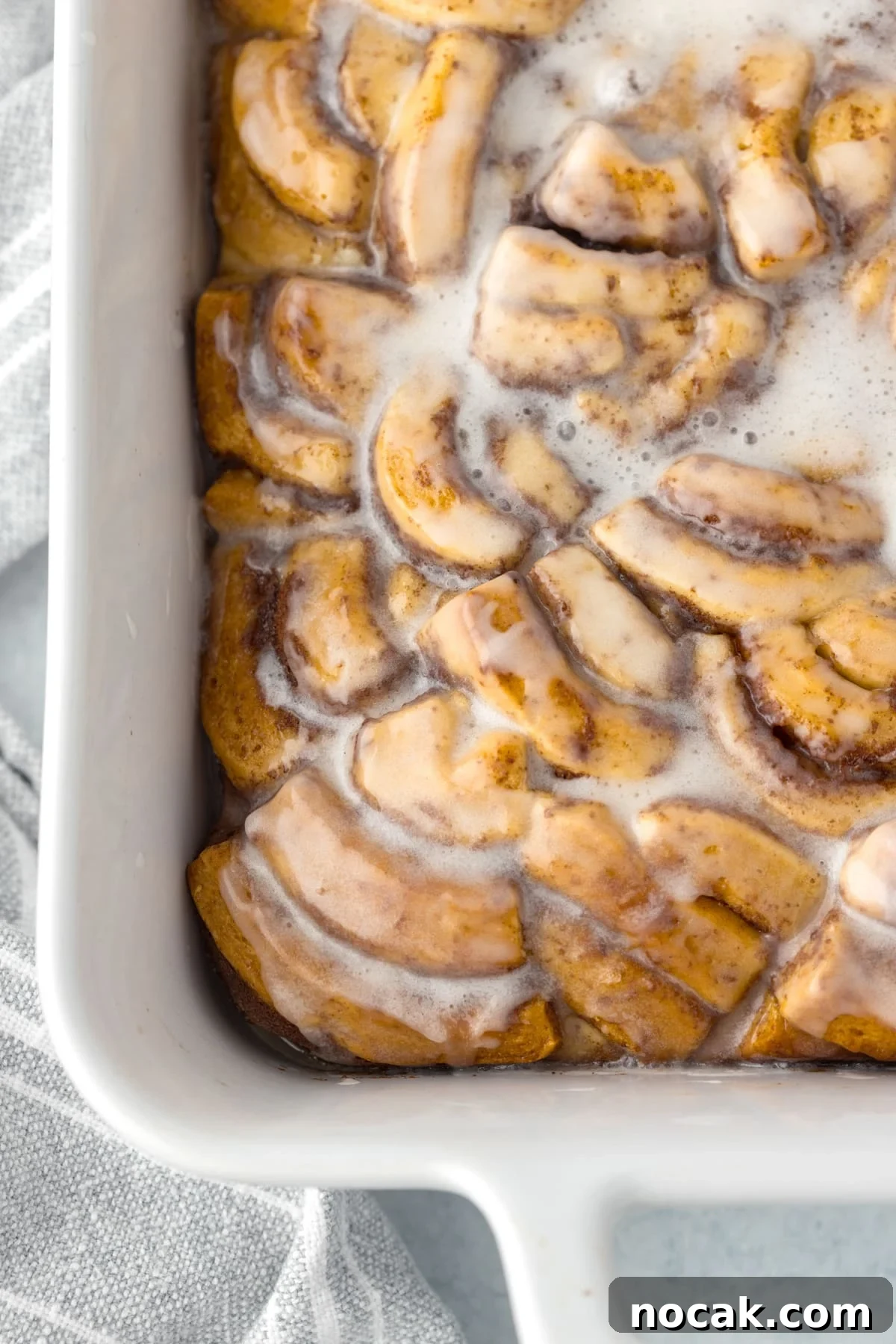 Cinnamon Roll Casserole Breakfast Bake Recipe 14 A baking dish filled with cinnamon roll pieces, baked and topped with icing.