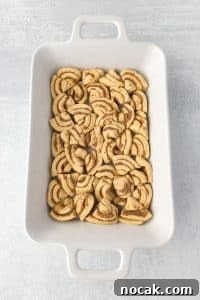 Cinnamon Roll Casserole Breakfast Bake Recipe 21 A casserole dish with cinnamon rolls sliced and fit into the dish in an even layer.