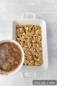 Cinnamon Roll Casserole Breakfast Bake Recipe 23 Pouring a custard mixture over a baking dish filled with cinnamon roll pieces.