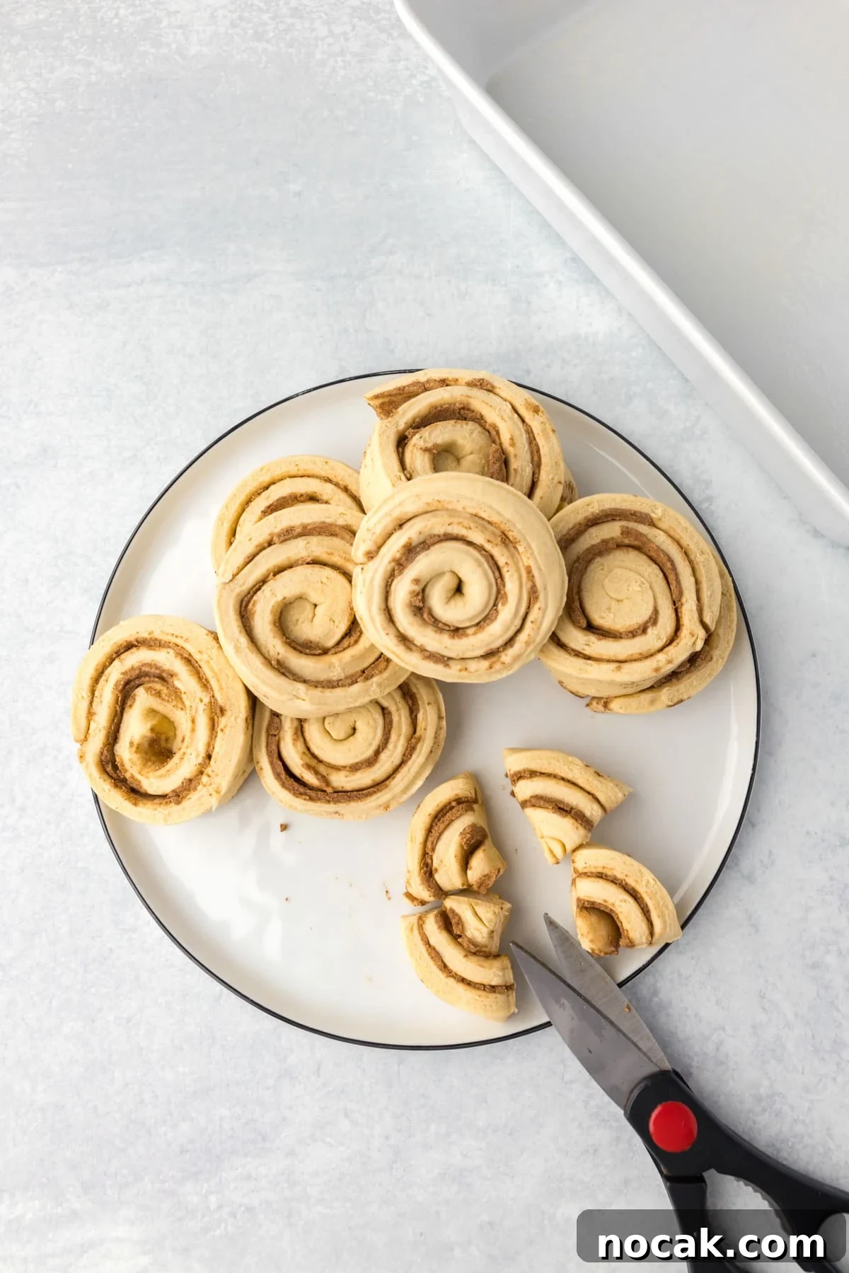 Cinnamon Roll Casserole Breakfast Bake Recipe 4 Slicing cinnamon rolls into quarters with scissors.