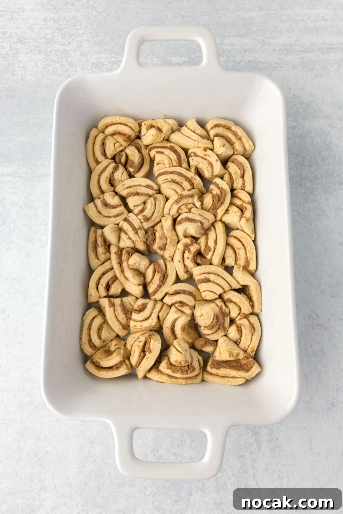 Cinnamon Roll Casserole Breakfast Bake Recipe 5 A casserole dish with cinnamon rolls sliced and fit into the dish in an even layer.