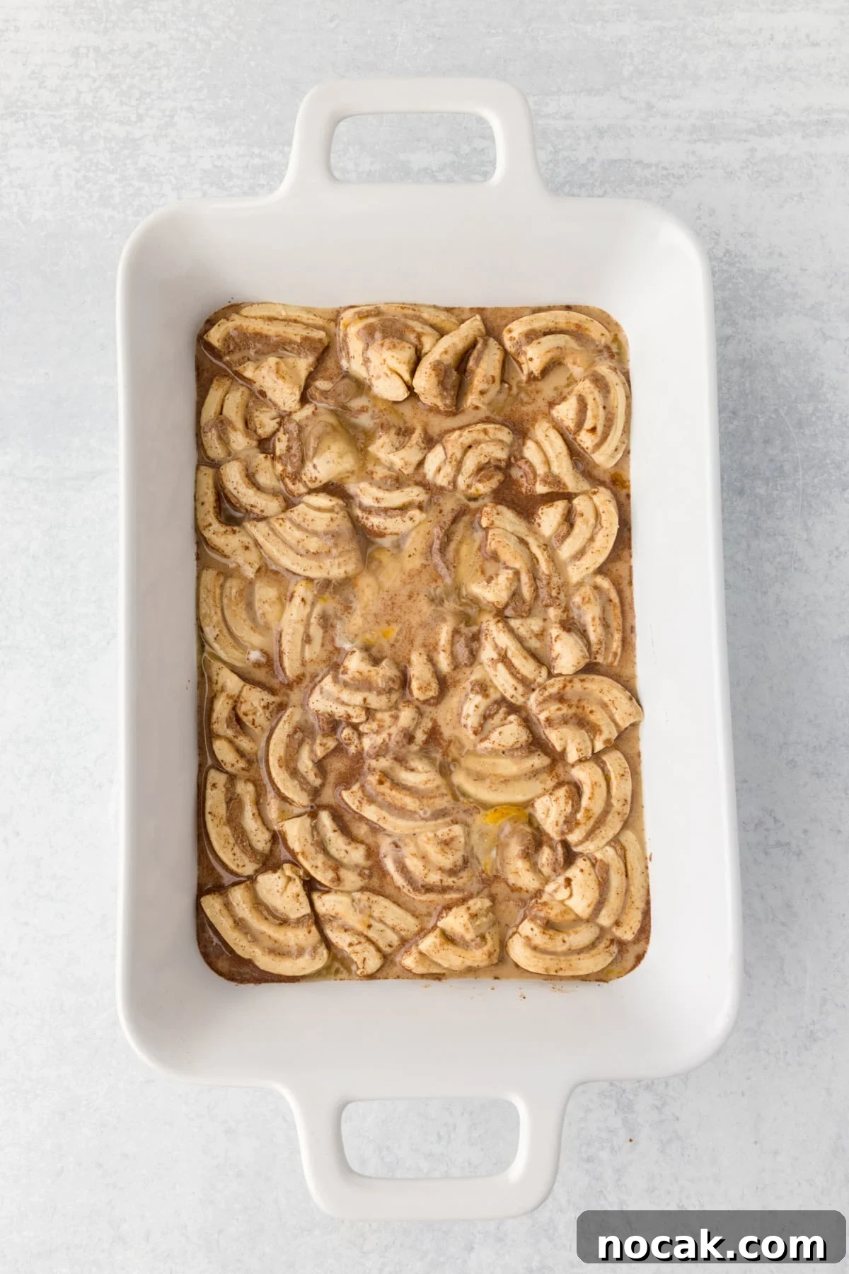 Cinnamon Roll Casserole Breakfast Bake Recipe 9 A baking dish with sliced cinnamon rolls and a custard base in it.