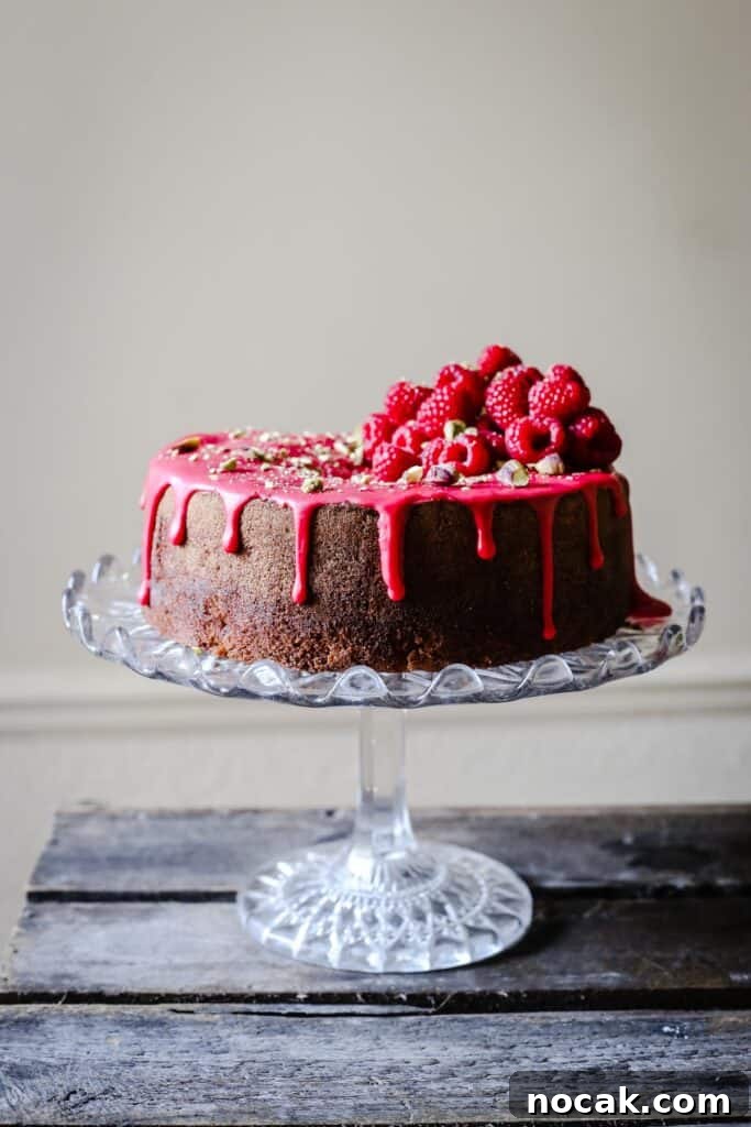 Gluten-Free Raspberry and Pistachio Cake Recipe 2 Raspberry Pistachio Cake sitting on a cake stand on a wooden table