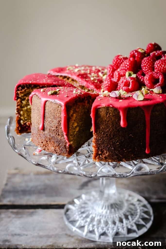 Gluten-Free Raspberry and Pistachio Cake Recipe 4 Sliced Raspberry Pistachio Cake sitting on a cake stand on a wooden table