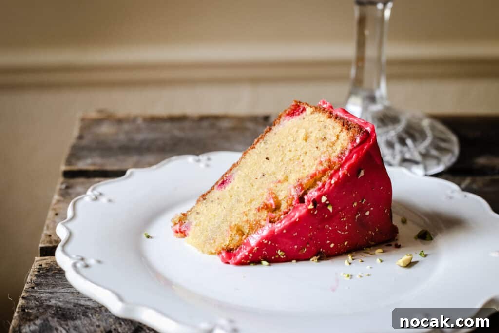 Gluten-Free Raspberry and Pistachio Cake Recipe 7 A slice of Raspberry Pistachio Cake on a white plate on a wooden table
