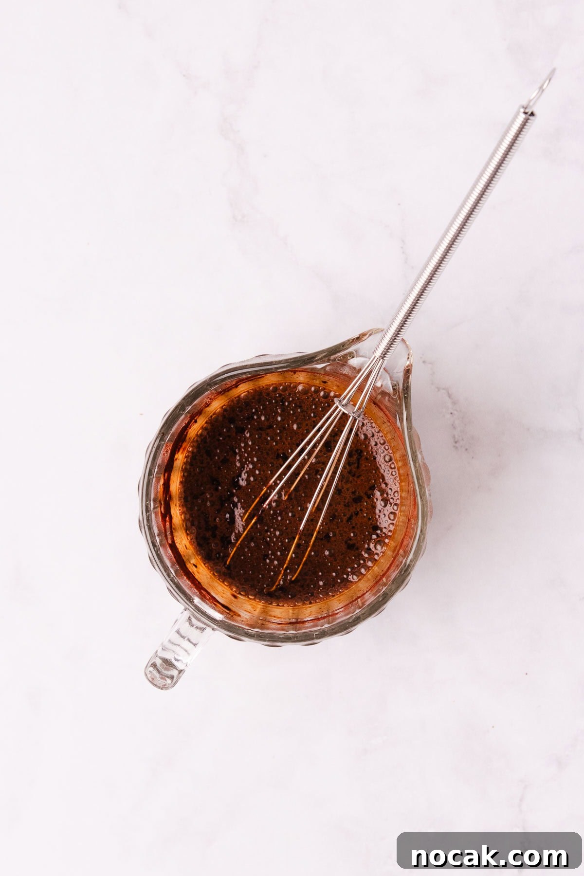 Creamy Mocha Milkshake Recipe: How to Make the Perfect Coffee Chocolate Shake 5 A small glass jug with coffee and cocoa mixed together, with a small metal whisk.