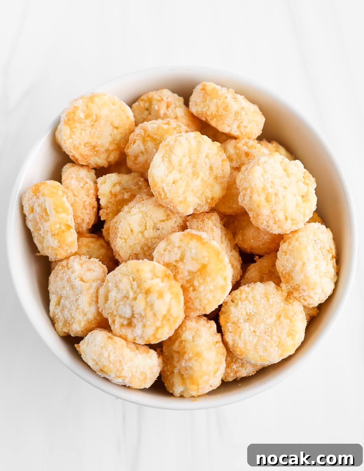 A bowl filled with frozen/uncooked tater tots.