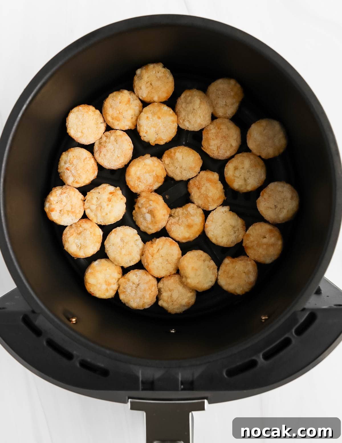An air fryer with frozen crispy crowns inside.