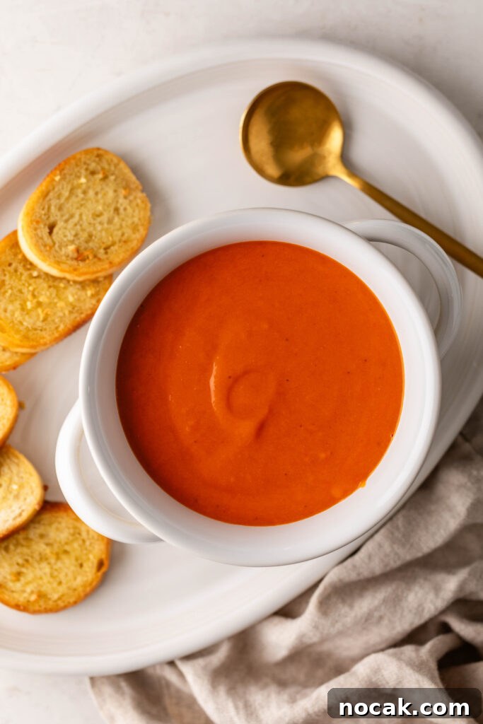 Creamy Sheet-Pan Roasted Tomato Soup 12 creamy roasted tomato soup in a white bowl on a plate with garlic crostini