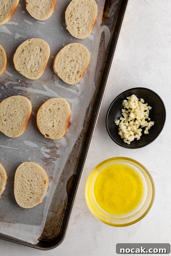 Creamy Sheet-Pan Roasted Tomato Soup 13 sliced baguette pieces on a parchment lined sheet pan with minced garlic and olive oil