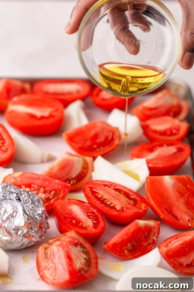 Creamy Sheet-Pan Roasted Tomato Soup 7 pouring olive oil over tomatoes and onions