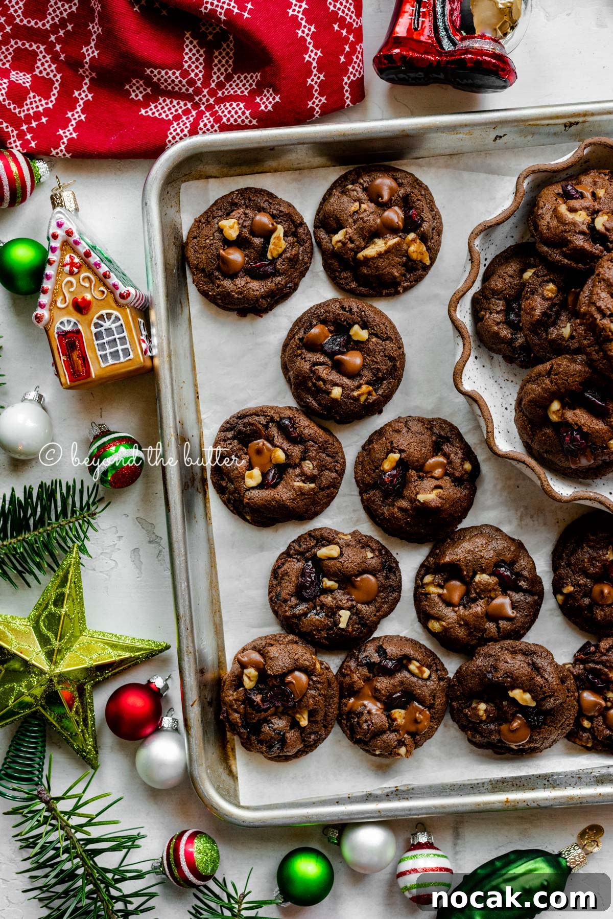 Dark Chocolate Cranberry Walnut Cookie Recipe for Rich, Chewy Treats 5 Parchment paper lined baking sheet with dark chocolate cranberry walnut cookies surrounded Christmas tree ornaments | All Images © Beyond the Butter®
