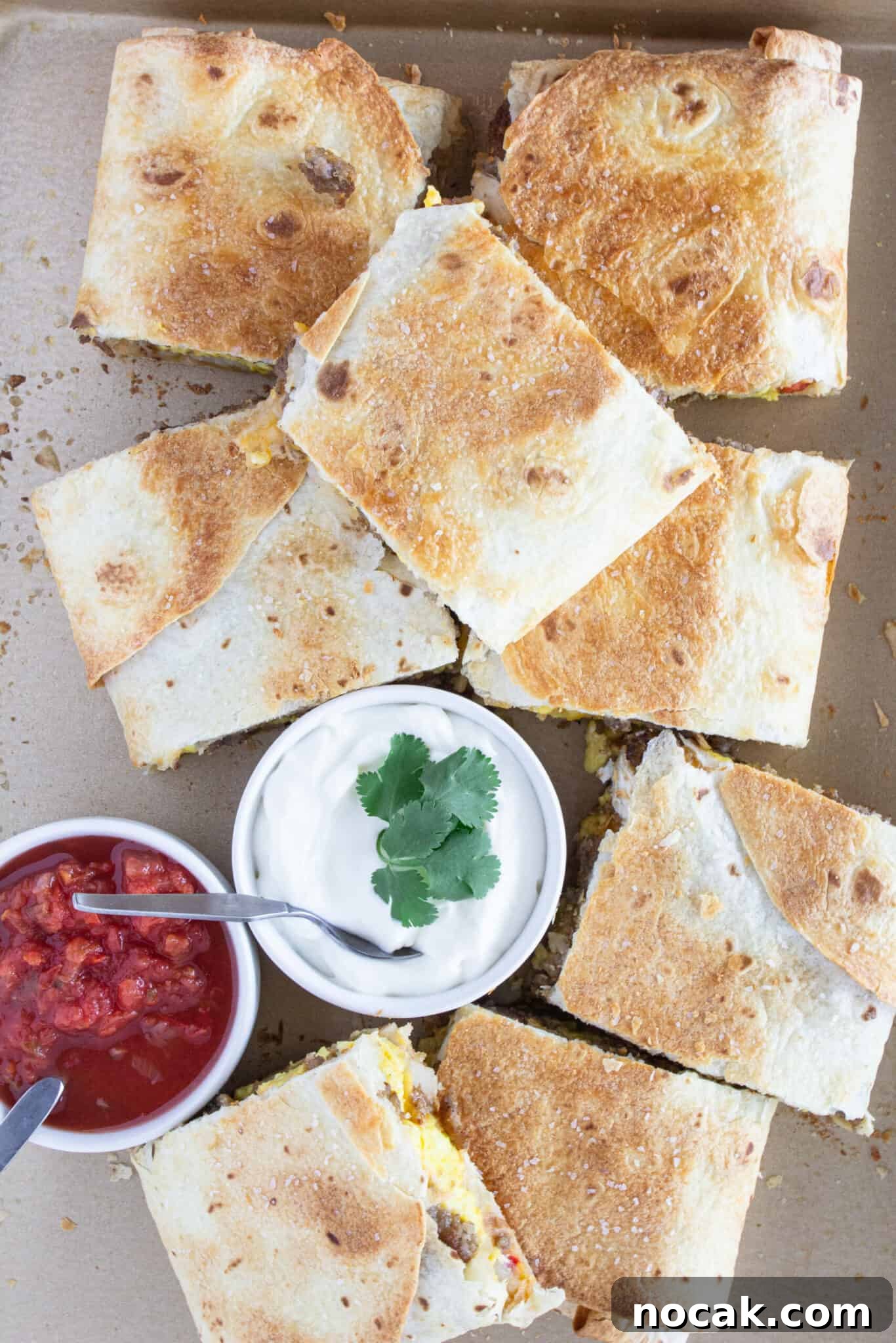 Looking down at a Sheet Pan Breakfast Quesadilla with sour cream and cilantro.