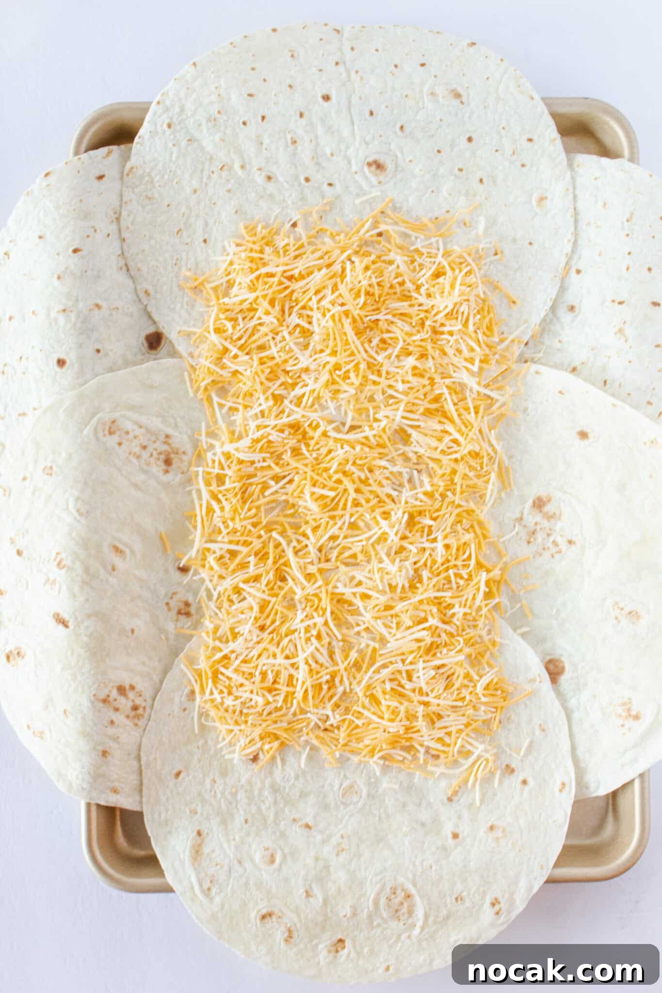 Laying out the tortilla and adding the cheese to the top.